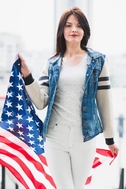 Mulher orgulhosa andando com grande bandeira dos EUA