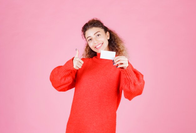 Foto grátis mulher segurando seu novo cartão de visita e mostrando sinal de mão de prazer.