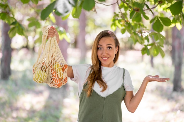 Foto grátis mulher segurando uma sacola biodegradável com vegetais e frutas