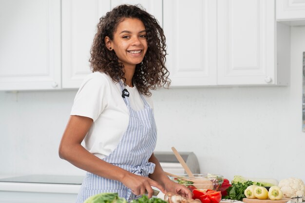 Mulher sorridente, cozinhando e olhando para o fotógrafo