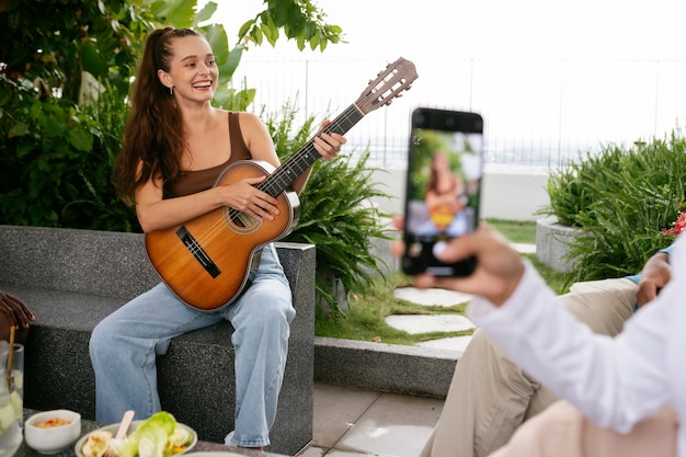 Mulher sorridente de tiro completo tocando violão