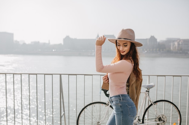 Foto grátis mulher sorridente magro em jeans e camisa rosa posando com bicicleta