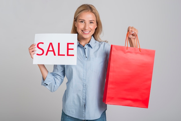 Foto grátis mulher sorridente segurando cartaz de venda e sacola de compras