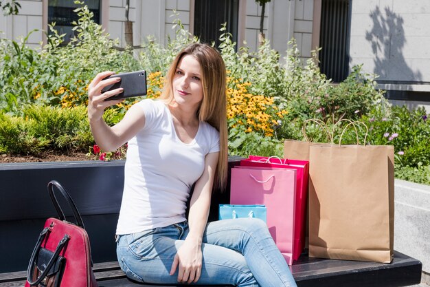 Mulher viciada em compras, tendo selfie no smartphone