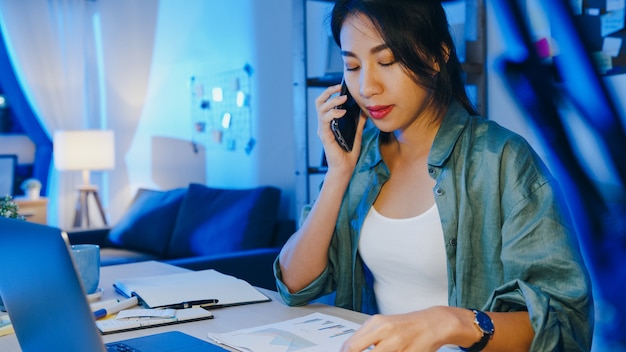 Foto grátis mulheres autônomas da ásia usando laptop falam no telefone ocupado empresário trabalhando distante na sala de estar.