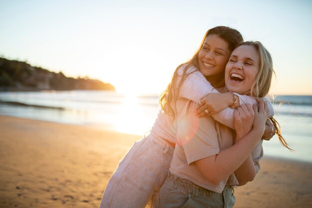 Mulheres felizes de tiro médio abraçando na praia