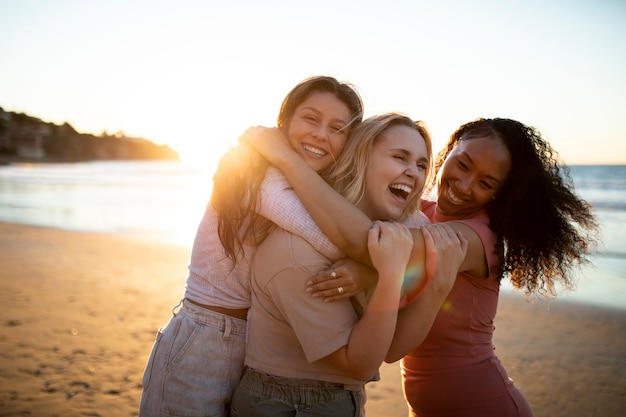 Mulheres sorridentes de tiro médio abraçando na praia