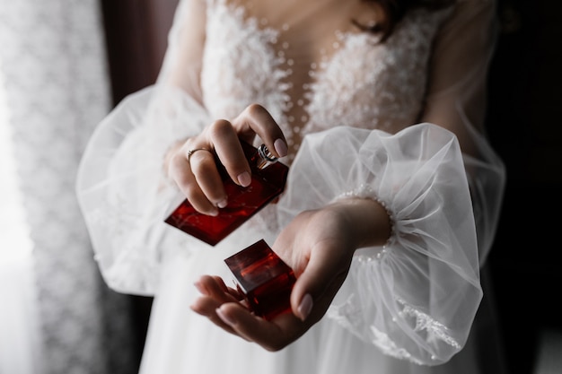 Foto grátis noiva de vestido branco elegante, com mangas bonitas e perfume nas mãos