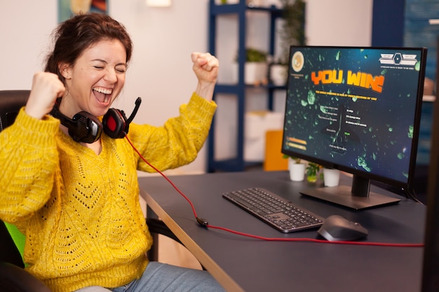 Foto grátis o jogador alegre comemora a vitória do jogo de tiro espacial on-line em um poderoso computador pessoal