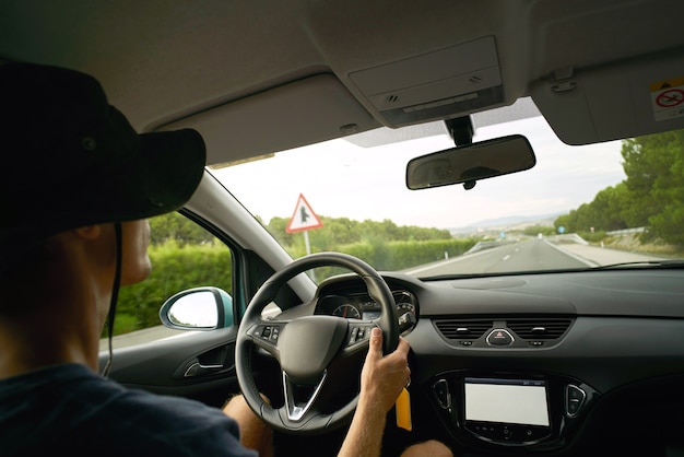 O motorista viaja em seu carro na rodovia, vista de dentro do carro. Mãos no volante, clima frio de verão