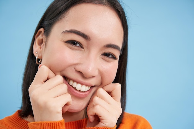 Foto grátis o retrato de beleza e cuidados com a pele de uma mulher japonesa sorridente e feliz toca sua pele clara e brilhante