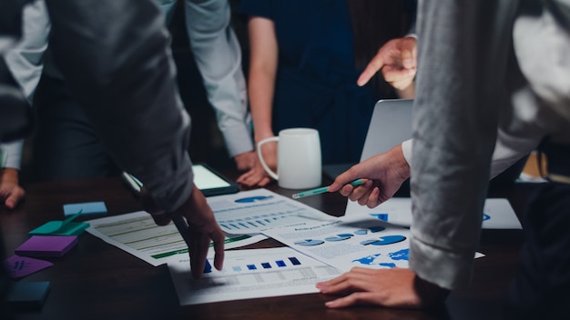 Foto grátis os empresários e mulheres de negócios milenares da ásia que encontram idéias de brainstorming sobre novos colegas do projeto de papelada trabalhando juntos planejando a estratégia de sucesso desfrutam do trabalho em equipe no pequeno escritório noturno moderno.