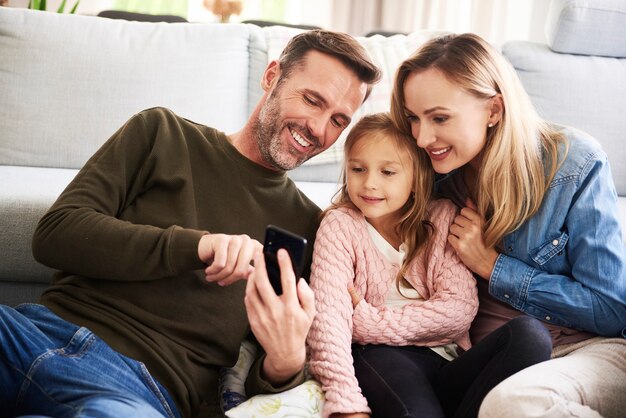 Pais e filha olhando para o celular