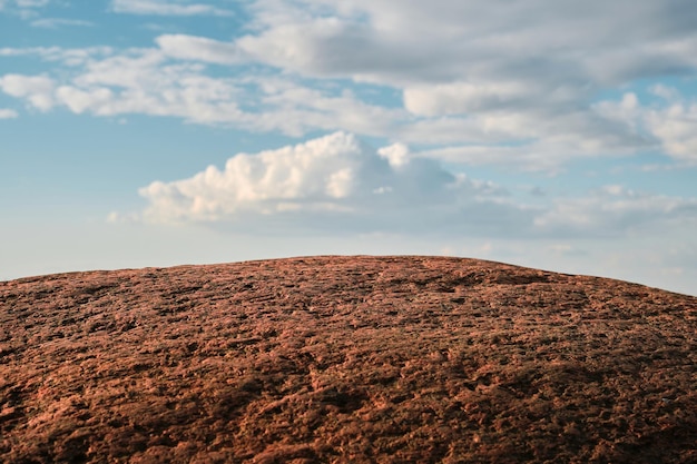 Foto grátis pedra de granito vermelho contra um céu azul com ideia de papel de parede de foco seletivo de nuvens