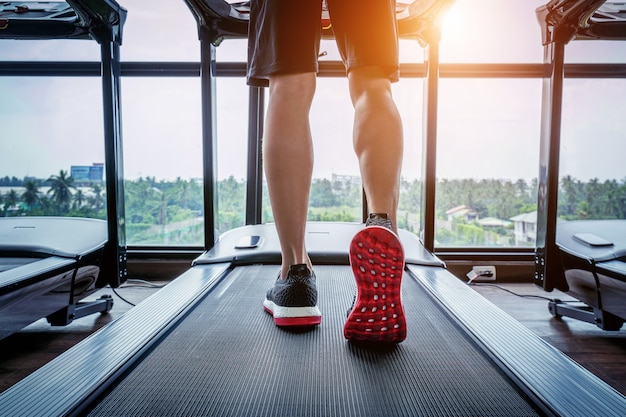 Pés masculinos de tênis correndo na esteira na academia. Conceito de exercício.