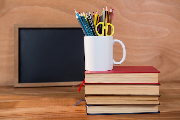 Pilha de livros com lápis colorido em uma caneca