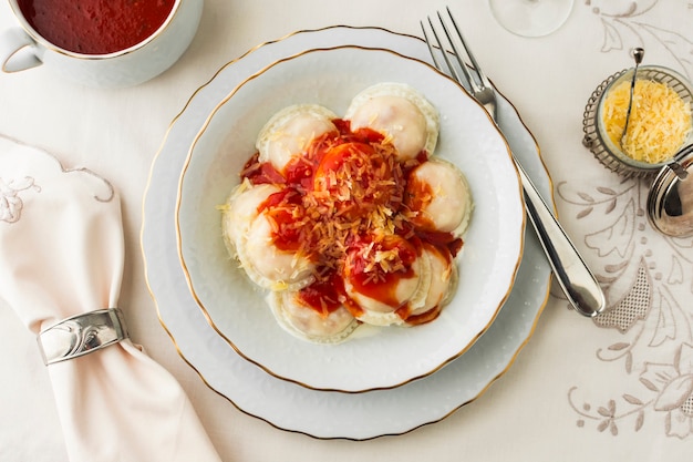 Foto grátis ravioli com molhos de tomate e queijo ralado na tigela de cerâmica contra a toalha de mesa