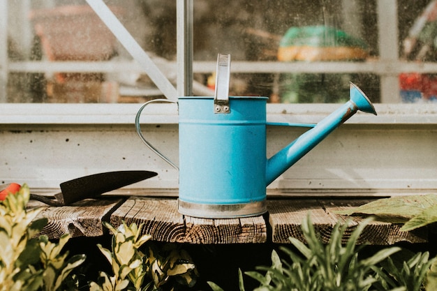 Foto grátis regador azul com espátula na mesa de madeira