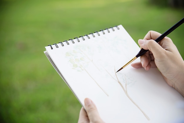 Foto grátis relaxe a mulher pintando o trabalho de arte em aquarela na natureza da floresta de jardim verde