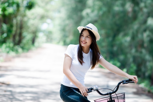 Retrato da mulher bonita nova que monta uma bicicleta em um parque.