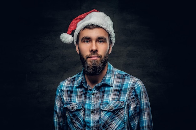 Foto grátis retrato de estúdio de homem barbudo vestido com uma camisa xadrez e chapéu de papai noel isolado em fundo cinza vinheta.