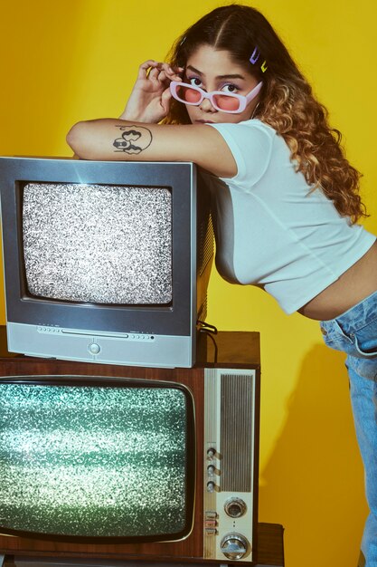 Retrato de jovem com estilo de moda dos anos 2000 posando com tv