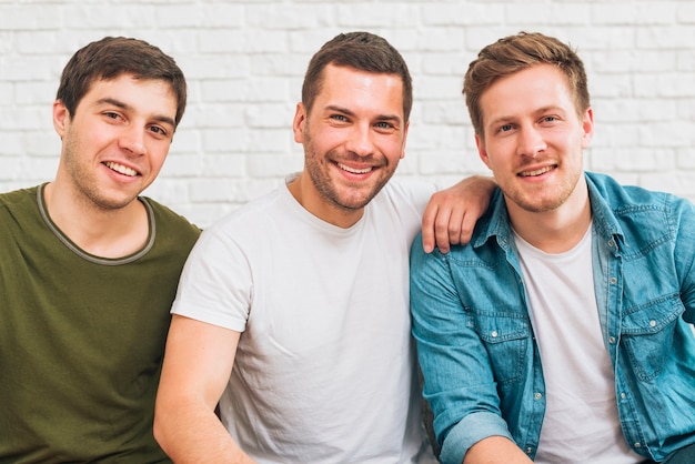 Foto grátis retrato, de, sorrindo, amigos masculinos, olhando câmera, contra, branca, parede tijolo