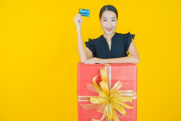 Retrato de uma bela jovem asiática sorrindo com caixa de presente vermelha em amarelo