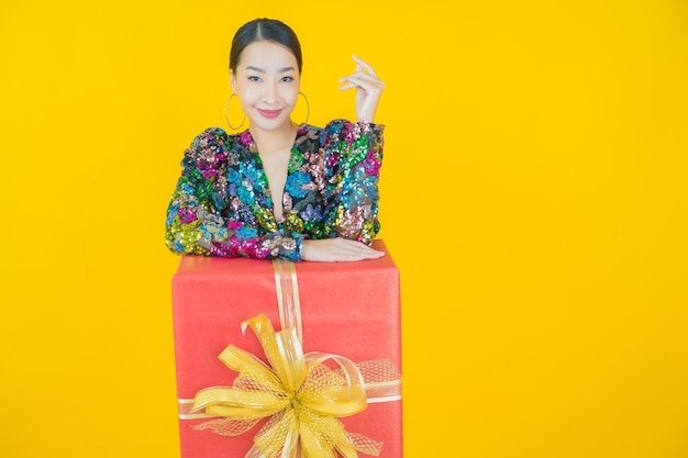 Retrato de uma bela jovem asiática sorrindo com caixa de presente vermelha em amarelo