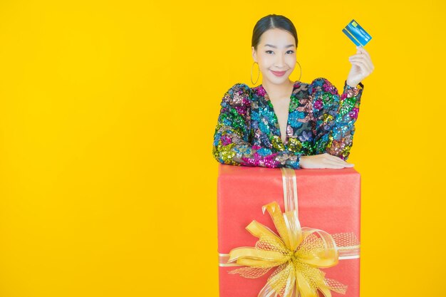 Retrato de uma bela jovem asiática sorrindo com caixa de presente vermelha em amarelo