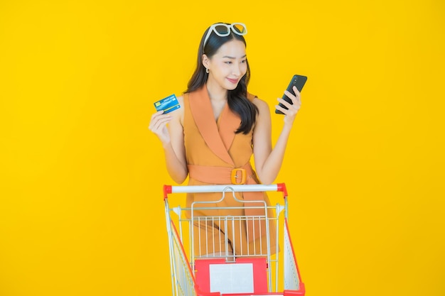 Foto grátis retrato de uma bela jovem asiática sorrindo com uma cesta de supermercado