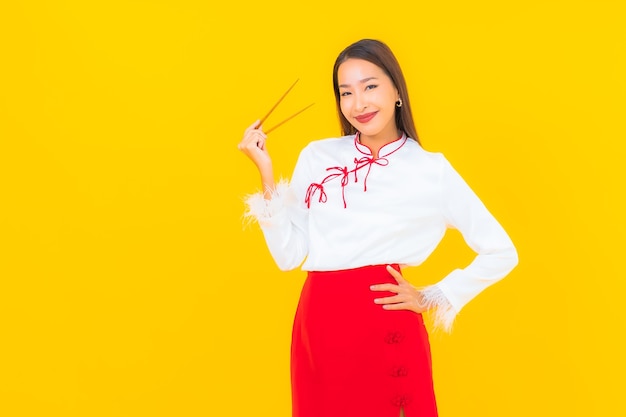 Foto grátis retrato linda jovem asiática com pauzinho pronto para comer em amarelo