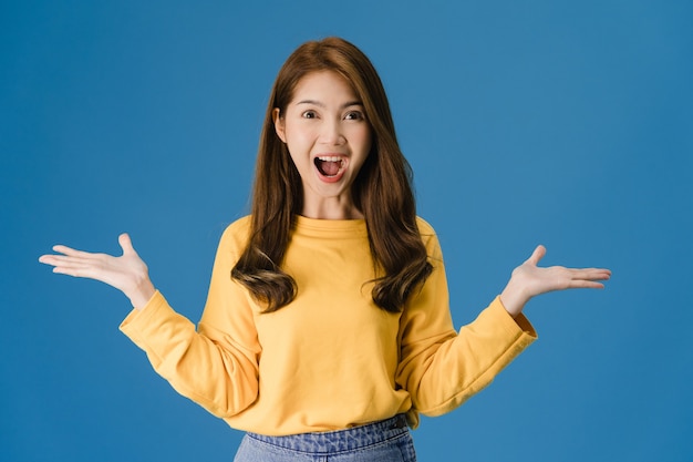 Foto grátis senhora jovem da ásia sentindo felicidade com uma expressão positiva, alegre surpresa funky, vestida com um pano casual e olhando para a câmera isolada sobre fundo azul. mulher feliz adorável feliz rejubila sucesso