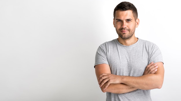 Foto grátis sorrindo jovem bonito com braço cruzou contra o pano de fundo branco