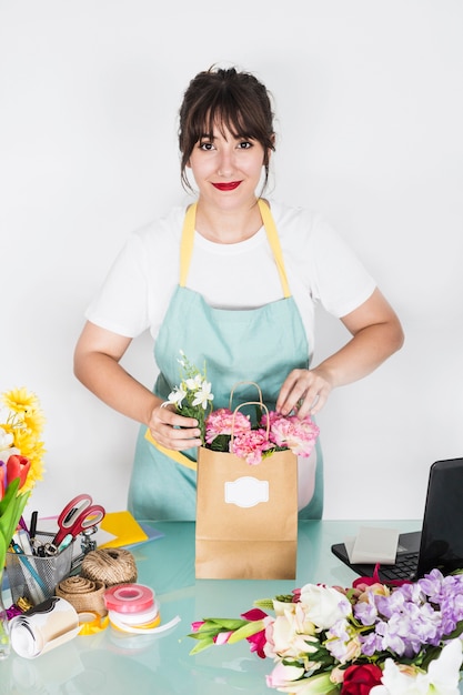 Foto grátis sorrindo, jovem, femininas, florista, com, flor, saco papel, ligado, escrivaninha