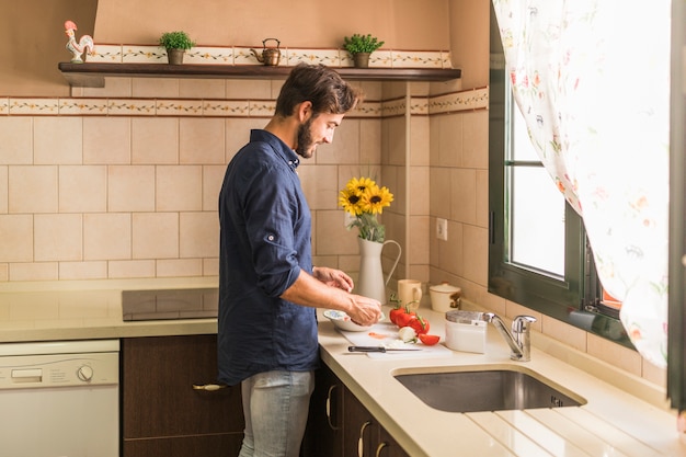 Foto grátis sorrindo jovem preparando salada na cozinha