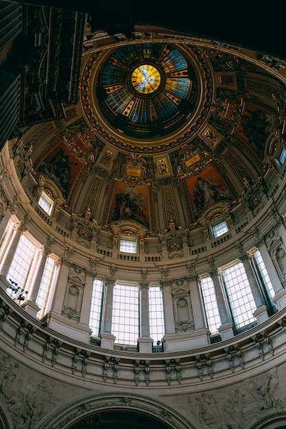 Foto grátis tiro de ângulo baixo do teto bonito e as janelas e pinturas em um prédio antigo