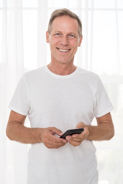 Foto grátis tiro médio sorridente homem segurando um smartphone