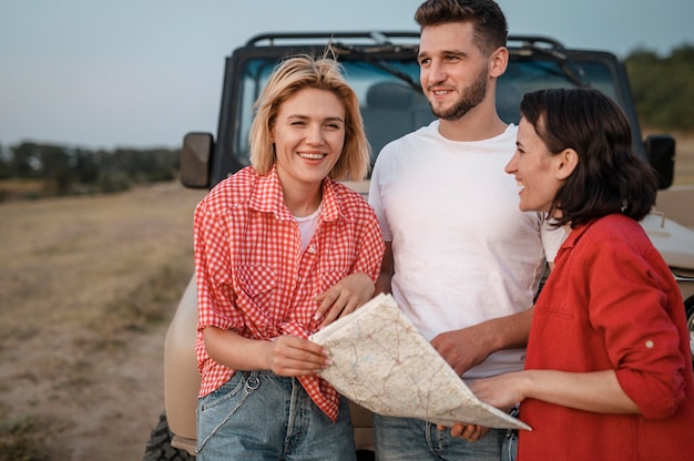 Foto grátis três amigos viajando de carro e verificando o mapa