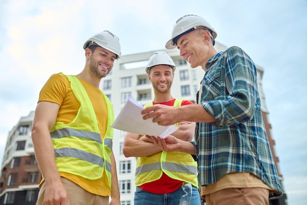 Foto grátis três homens com desenho discutindo no canteiro de obras