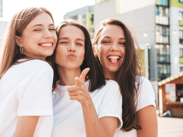 Três jovem e bela mulher hipster sorridente no verão da moda mesmas roupas Mulheres despreocupadas sexy posando no fundo da ruaModelos positivos se divertindo Abraçando Alegre e feliz