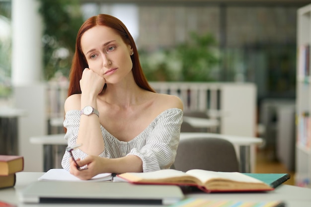 Foto grátis triste mulher sentada à mesa com livros