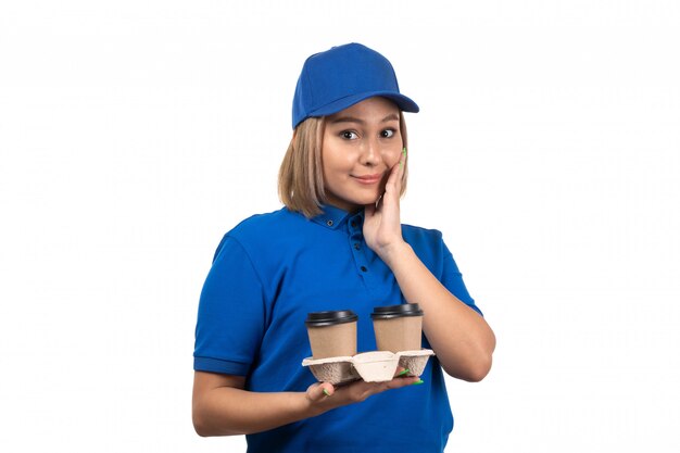 Uma jovem mensageira de uniforme azul segurando xícaras de café