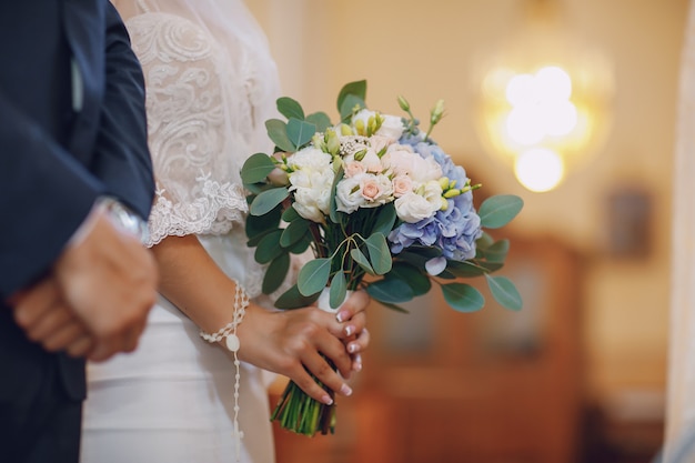 Foto grátis uma noiva jovem e bonita está de pé com o marido em uma igreja