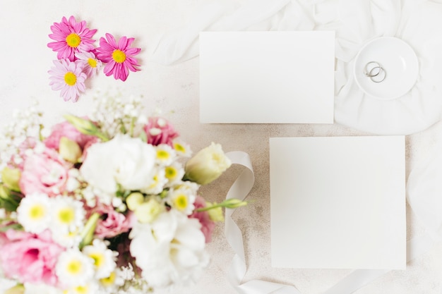 Foto grátis uma visão aérea de buquês de casamento com cartão branco e anéis em pano de fundo concreto