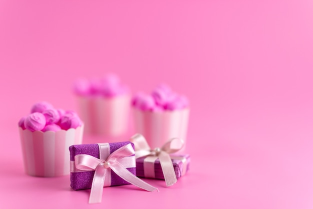 Foto grátis uma vista frontal de caixas de presente roxas junto com doces rosa em uma mesa rosa