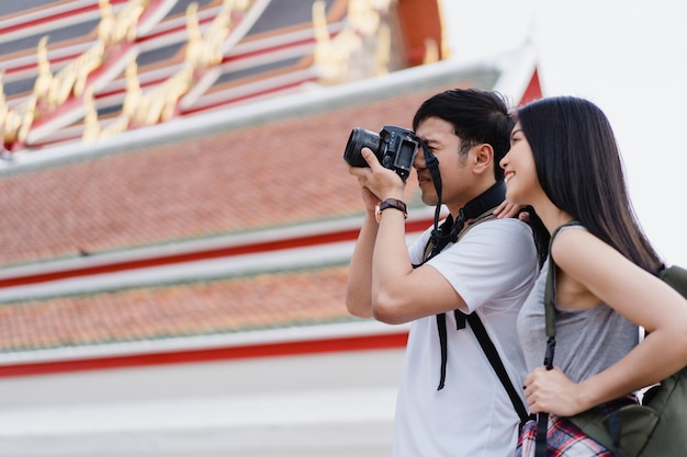 Foto grátis viajante casal asiático usando a câmera para tirar uma foto ao passar a viagem de férias em bangkok, tailândia