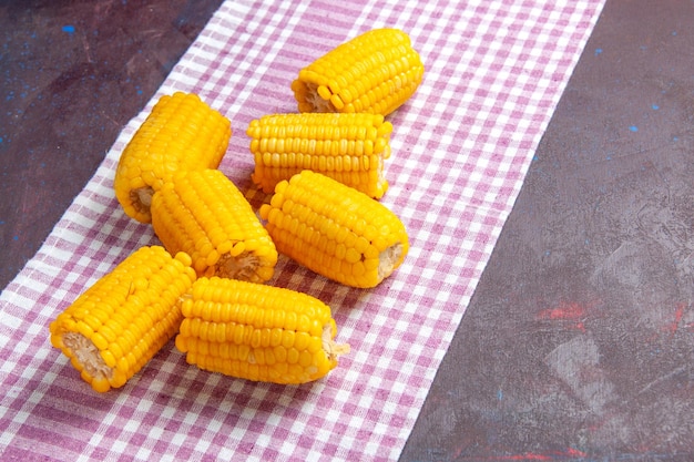 Visão frontal de grãos amarelos fatiados crus e frescos na superfície escura alimentos vegetais de milho crus frescos