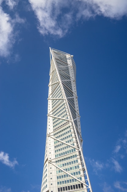 Foto grátis vista de baixo ângulo do turning torso sob um céu azul e luz do sol em malmo, na suécia