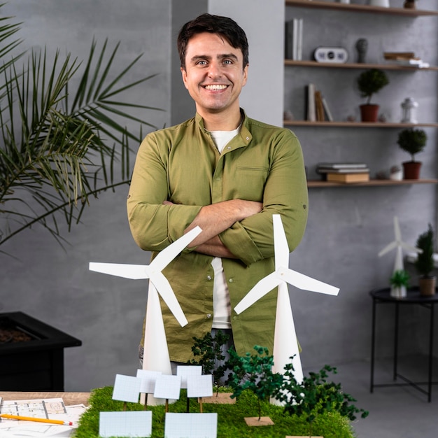 Foto grátis vista frontal de um homem sorridente trabalhando em um projeto de energia eólica ecologicamente correto com turbinas eólicas